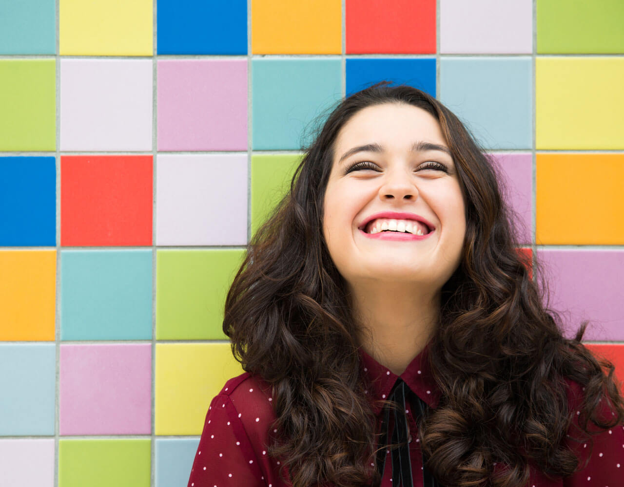  A young woman smiling against a colorful backdrop 