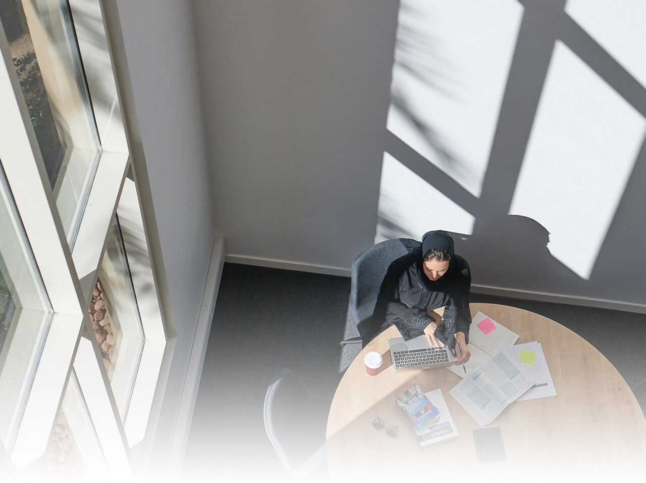 A woman researching on her laptop and books