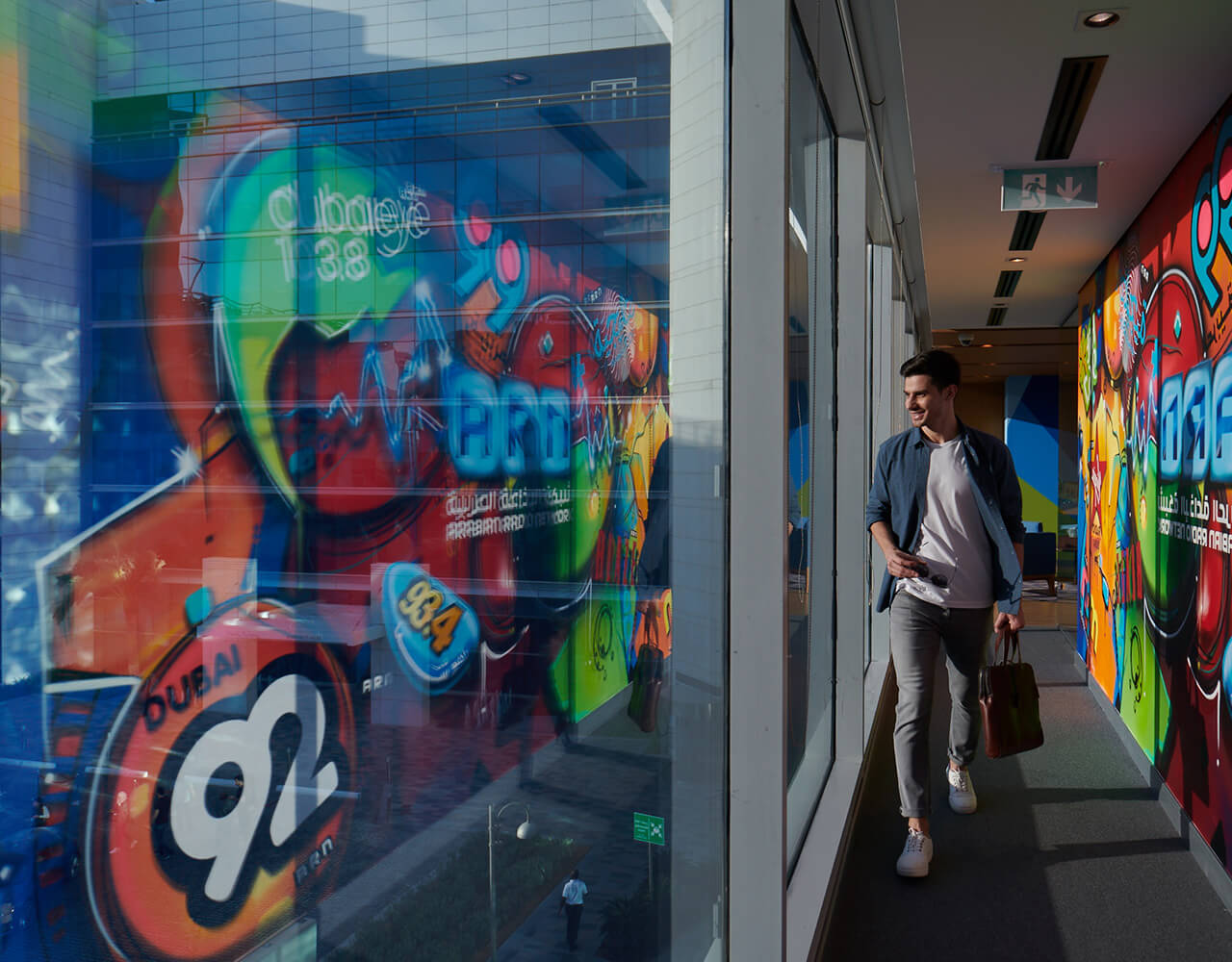 Smiling man walking and gazing at the companies in Dubai Studio City